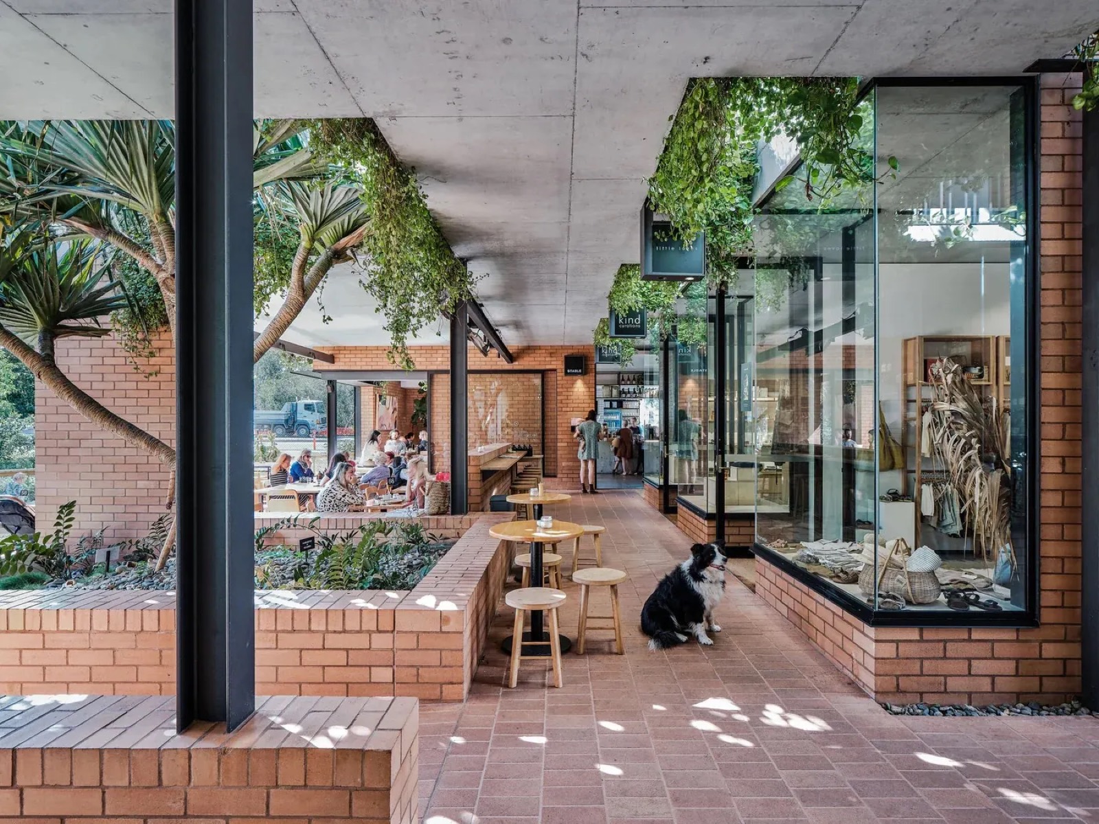 Another view of the Cornerstone Stores courtyard, red brick walls and greenery around a central gathering space