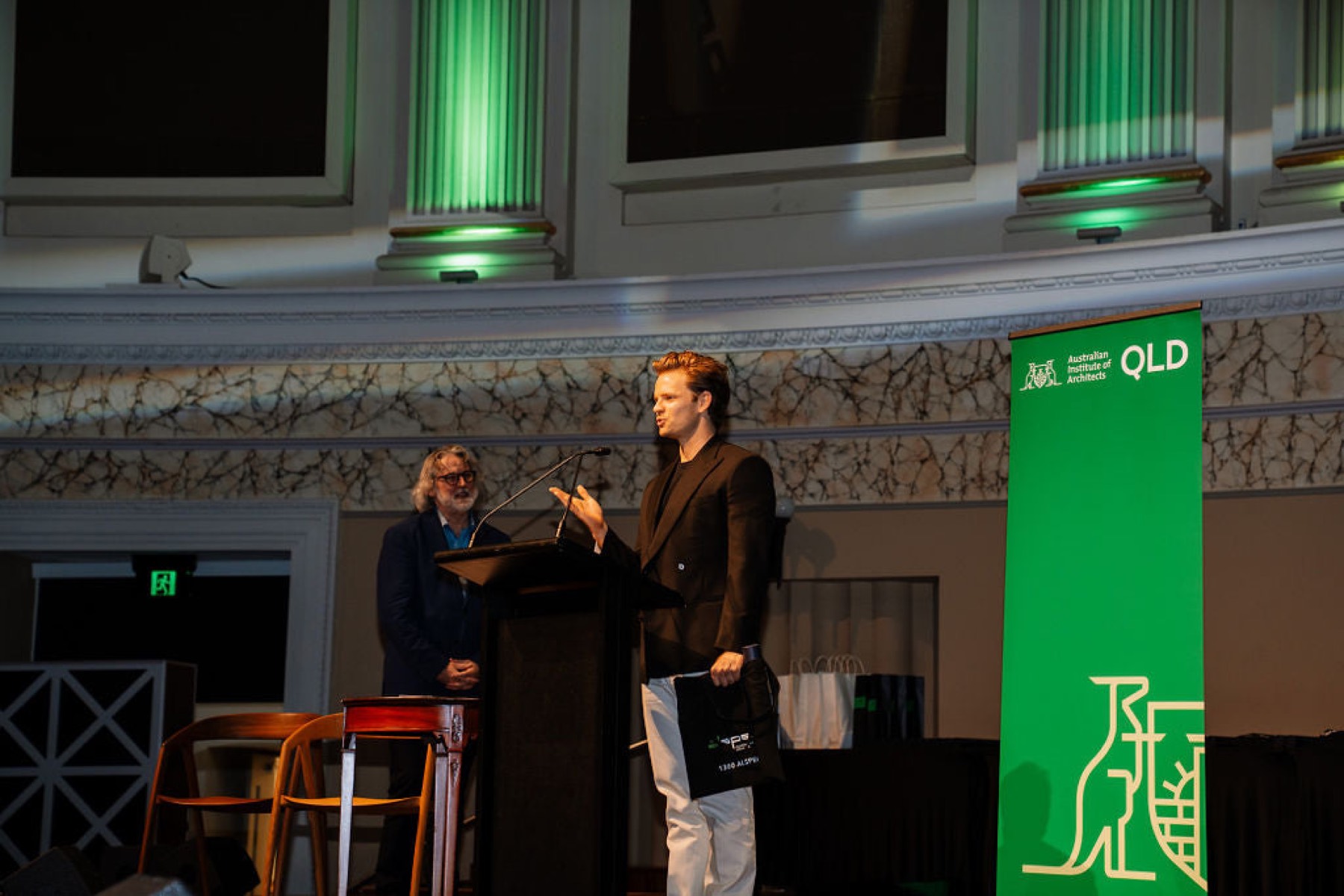 A documentary photograph of representatives accepting the 2024 National Architecture Award for The Warehouses at a podium